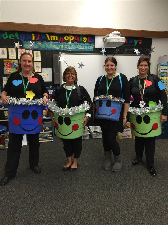 Four women teachers are shown wearing buckets around their waists with smiley faces on them. They have hearts and stars taped to their shirts.