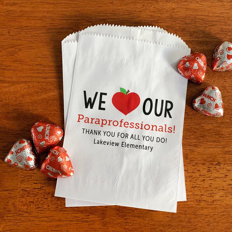 Una bolsa de papel blanca dice Amamos a nuestros paraprofesionales (Regalos para paraprofesionales)