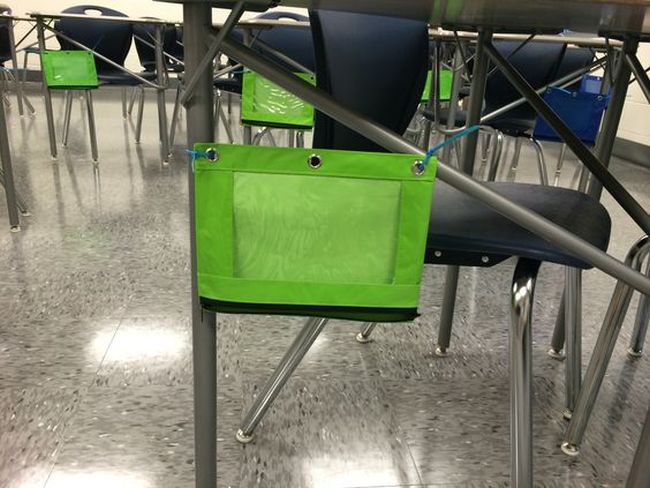 Bright green zippered pouch attached to student desk with zip ties