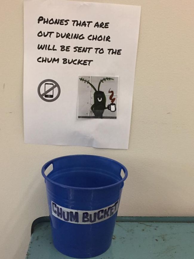 Blue bucket labeled Chum Bucket with sign reading Phones that are out during Choir will be sent to the Chum Bucket.