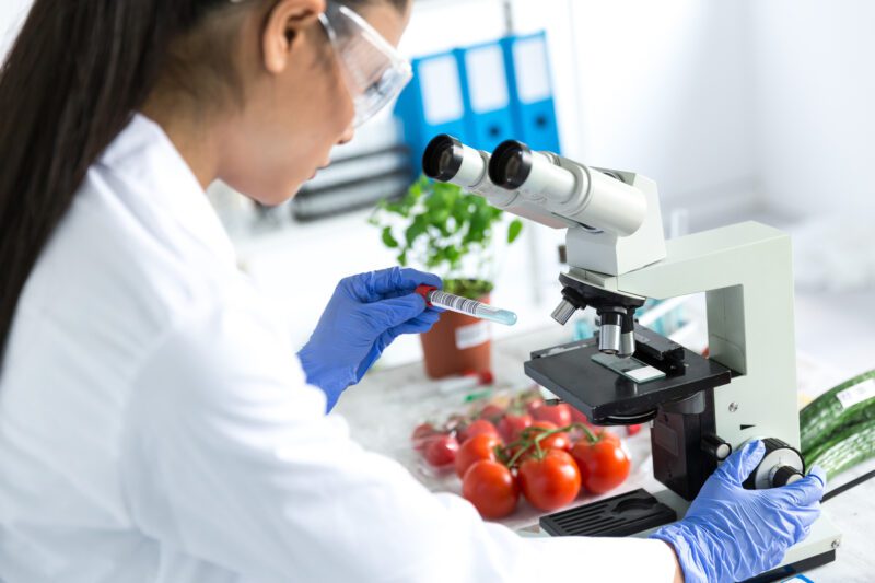 Female microbiologist using microscope in laboratoty