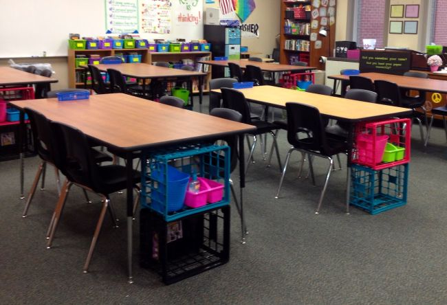 School classroom showing plastic crates stacked at tables to use as storage cubbies