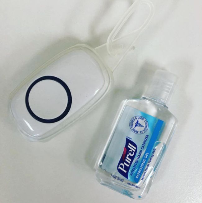 Mini bottle of Purell next to a doorbell remote in a plastic holder