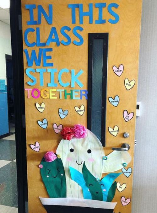 Classroom door decorated with a 3-D paper cactus and hearts with student names. Text reads In this class, we stick together.
