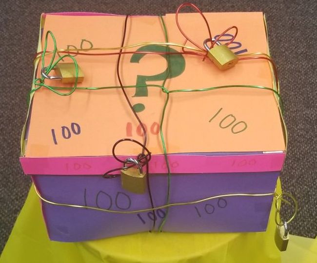 Colorful cardboard box wrapped in wire with multiple locks attached (Classroom Escape Room)
