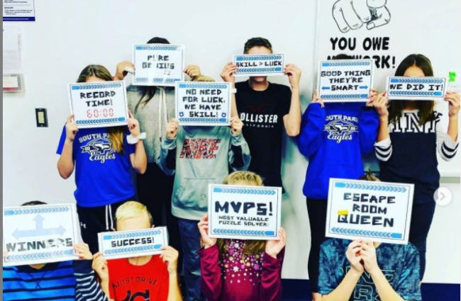Students celebrating the completion of an escape room by holding up signs