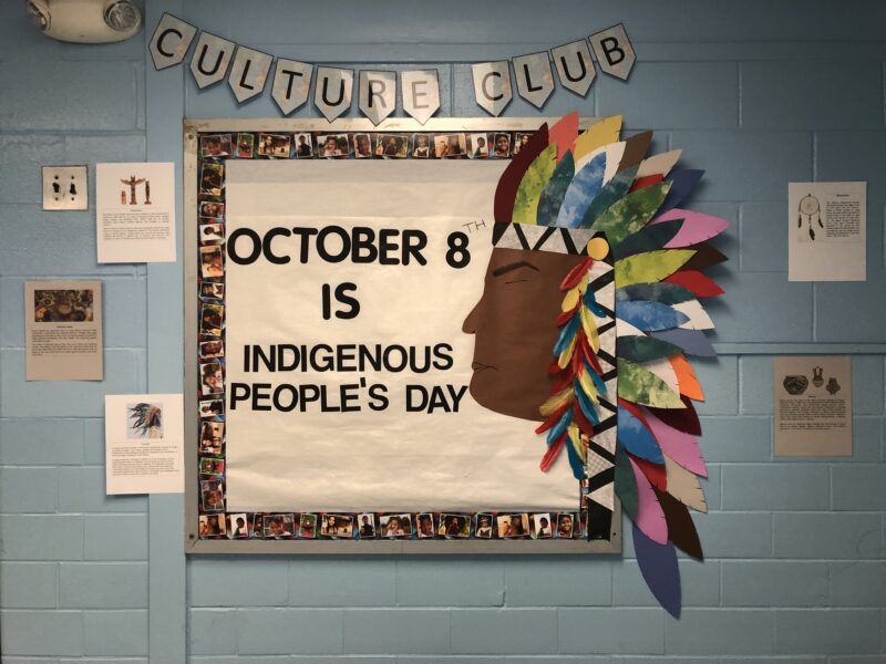 This October bulletin board idea shows a banner that reads Culture Club. The Board says October 8 is Indigenous People's Day. The left side of the board shows a Native American profile with a headdress on. 