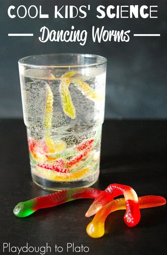 A clear glass of fizzy liquid with dancing gummy worms inside