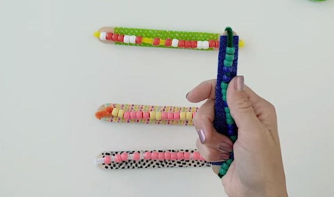 Student holding DIY fidgets made from wood craft stick, beads, pipe cleaner, and washi tape