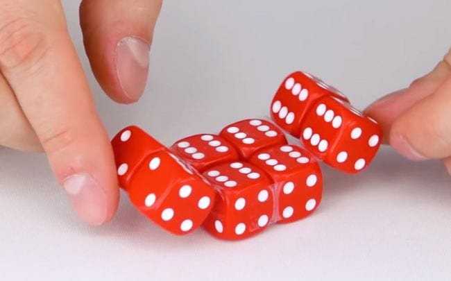 Student playing an infinity cube fidget toy made from red dice and transparent tape