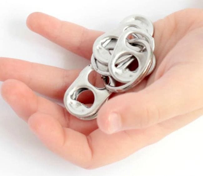 Child holding soda pop tops strung onto a keychain ring (DIY Fidgets)