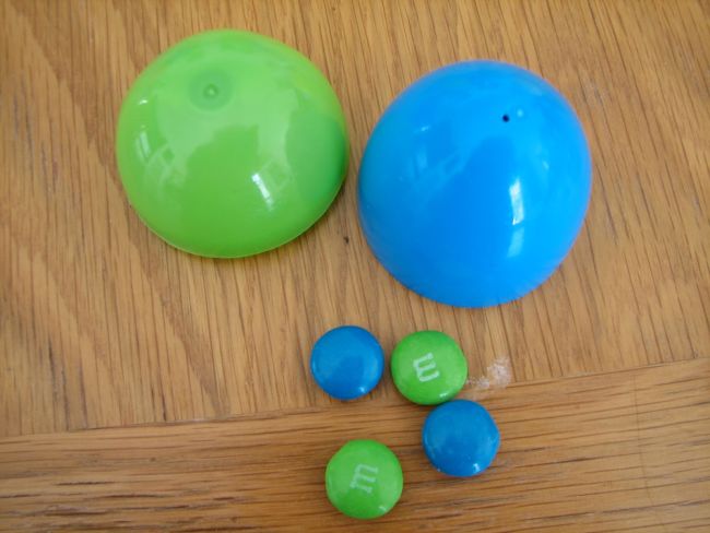 Green and blue halves of plastic egg with two blue and two green M&Ms