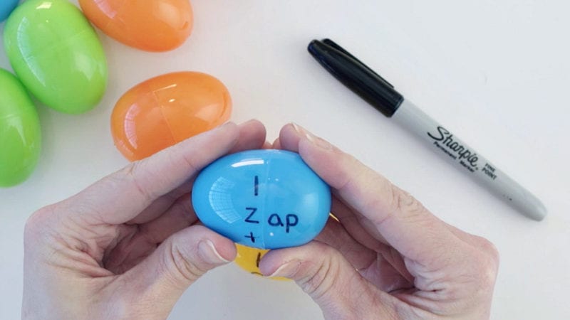 Hands twisting a plastic Easter egg with letters written on one half and "ap" on the other (Easter Egg Activities)