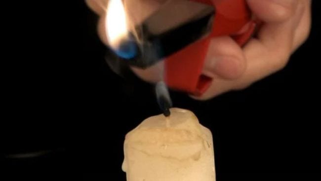 Student's hand holding a lighter over a candle that has just been blown out (Eighth Grade Science)