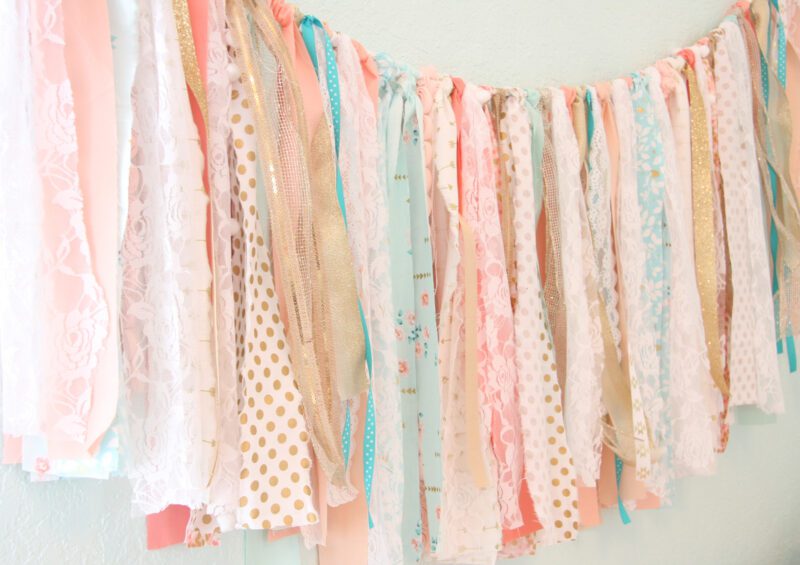 A garland is created from strips of different fabrics that are tied to a string in this easy art project for kids.
