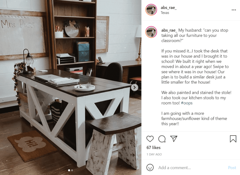 Centering a rustic, yet minimalistic, classroom is a large wooden island with white supports and a brown top being used as a teacher's desk.