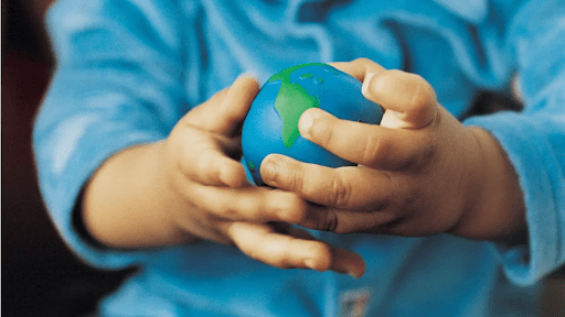 Child holding sensory ball that looks like the globe