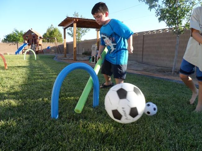 Child hitting an inflatable soccer ball through a hoop made from a pool noodle (Field Day Games)