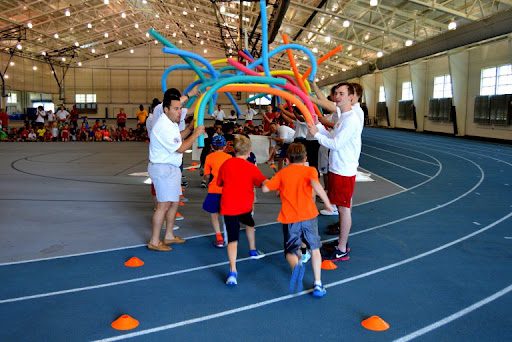 Kids running under foam noodles shaped like an arch