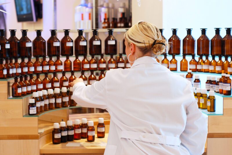 Chemist in white coat looking at different bottles