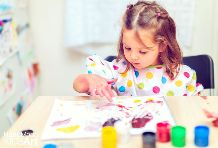Preschool girl finger painting, as an example of social-emotional activities