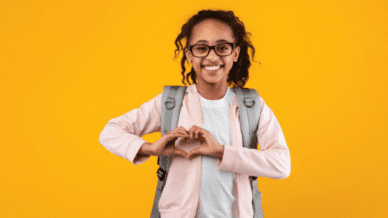 Girl wearing backpack making heart with hands, as an example of SEL activities