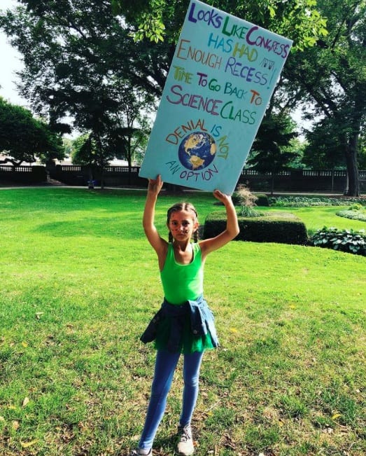 Girl in green shirt holding Global Climate Change Strike sign