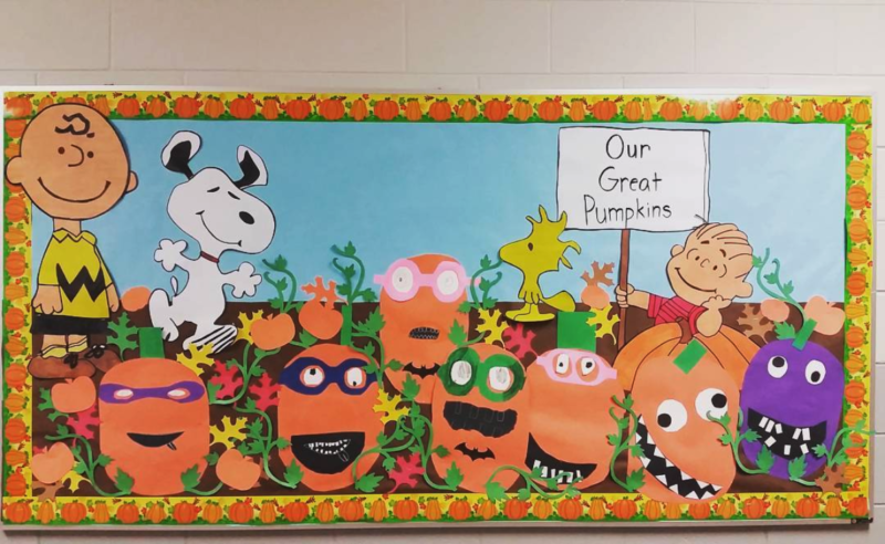 Fall bulletin boards like this one includes Charlie Brown, Linus, and Snoopy in a pumpkin patch. A sign reads "Our Great Pumpkins" and the pumpkins appear to be student made.