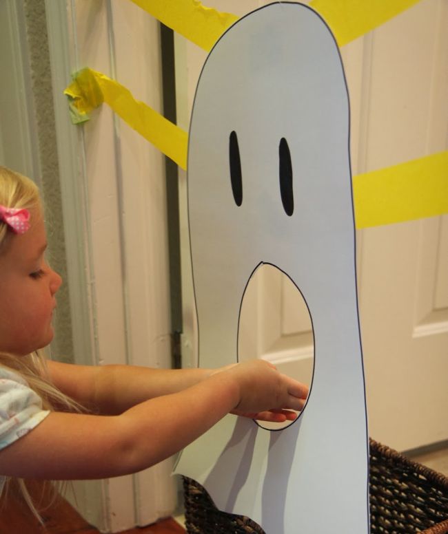 Young student feeding construction paper letters through a large paper ghost's mouth (Halloween Activities)