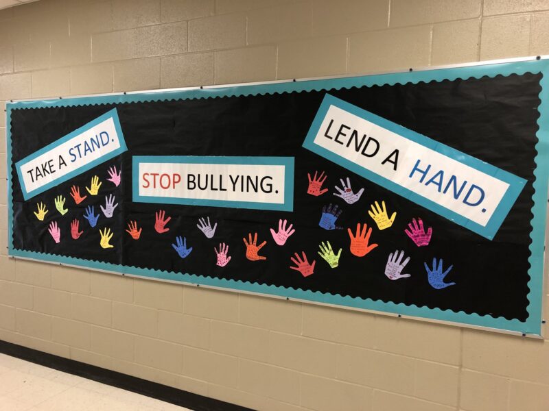 October bulletin board ideas includes this one on a black background. Multi-colored hands cover the board. The text reads 