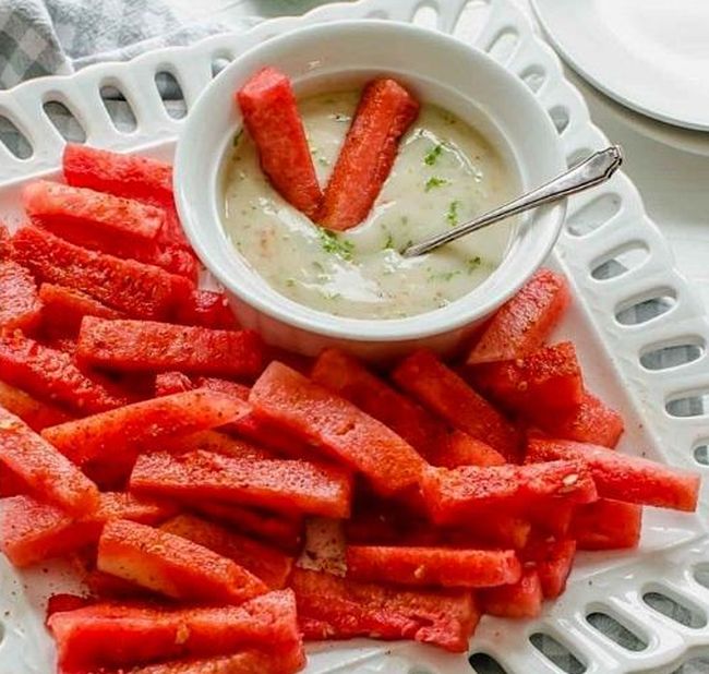 Watermelon sticks with coconut lime dip in a white bowl on a white plate