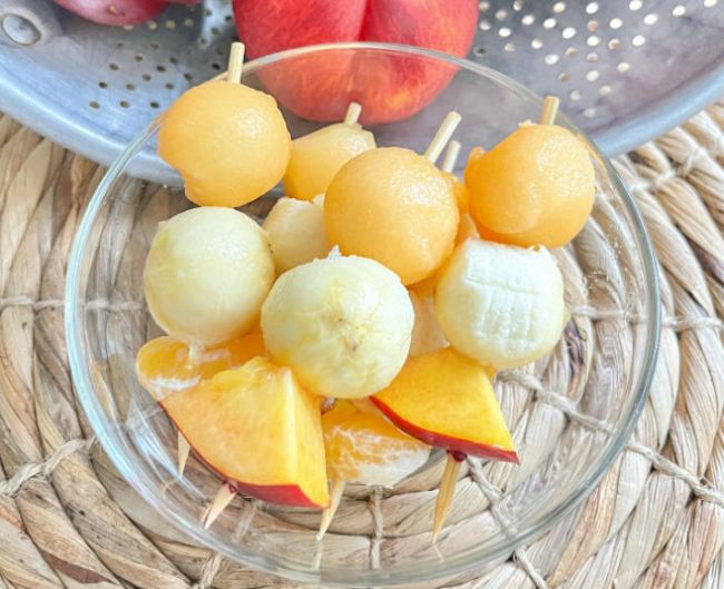 Fruit kebobs made of nectarines, mandarin slices, and balls of cantaloupe and banana (Healthy Snacks for Kids) 