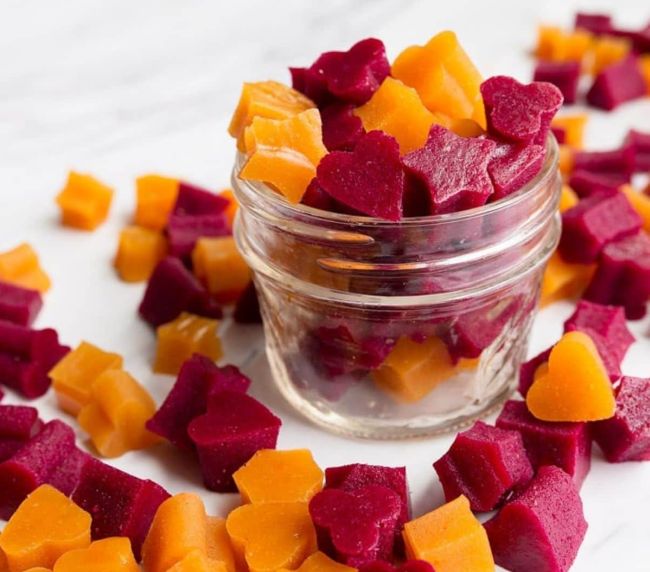 Red and orange gummies made from fruit and veggies in a small glass jar