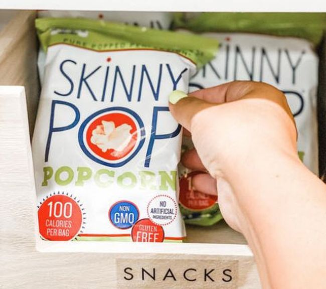 Hand reaching for a bag of SkinnyPop popcorn