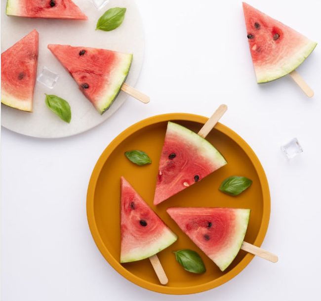 Slices of watermelon with wood popsicle sticks used to turn them into watermelon pops
