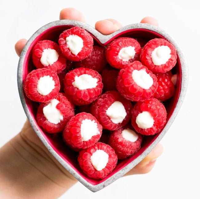 Raspberries filled with yogurt in a heart-shaped bowl