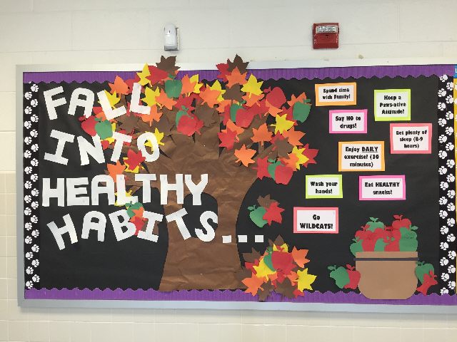 Text reads Fall into healthy habits in white writing. There is a tree with different colored foliage. A bushel of apples is also on the board.