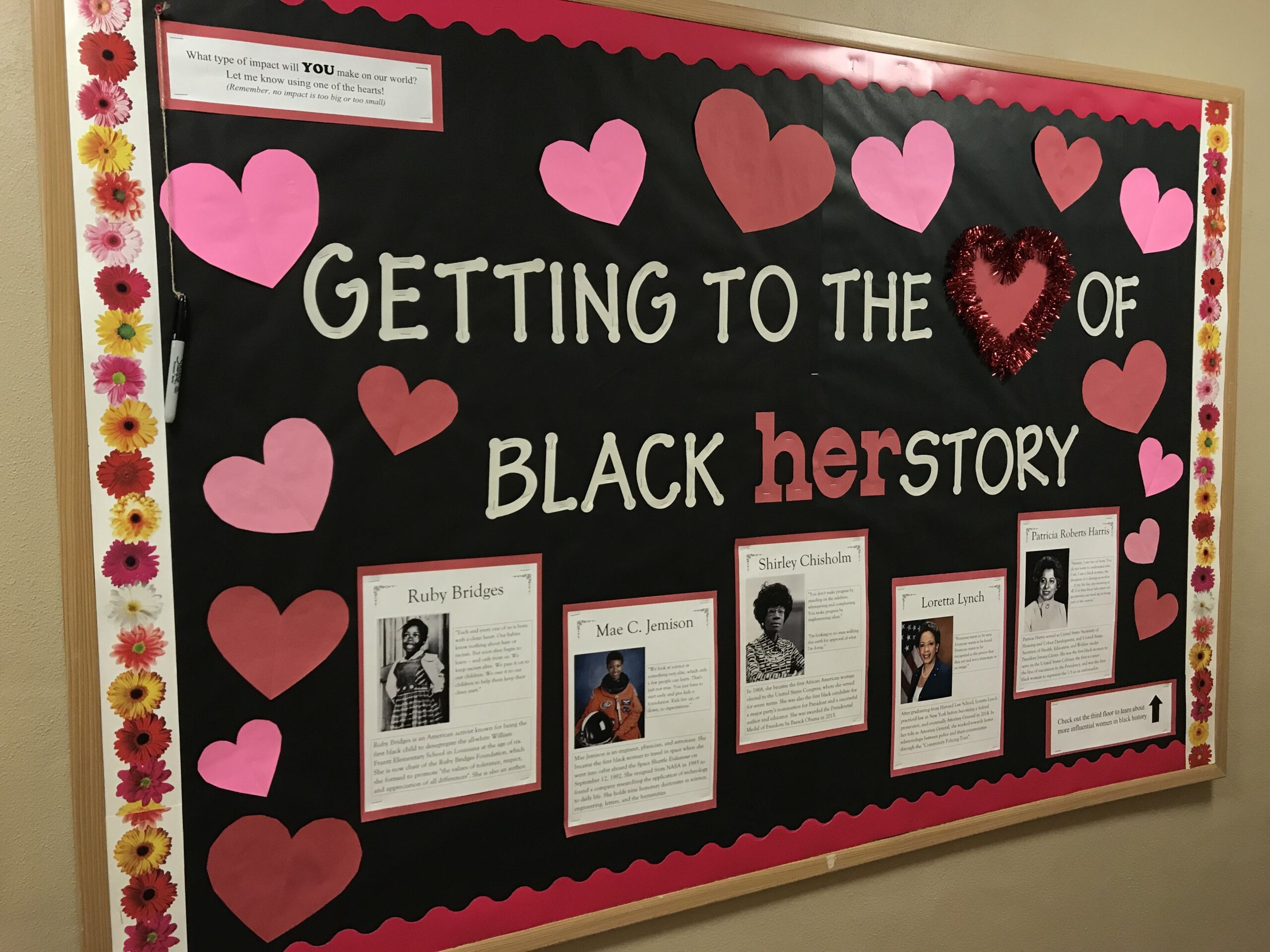 A black bulletin board says Getting to the heart of Black herstory. There are pink and red hearts on the border and photos and descriptions of famous Black women.