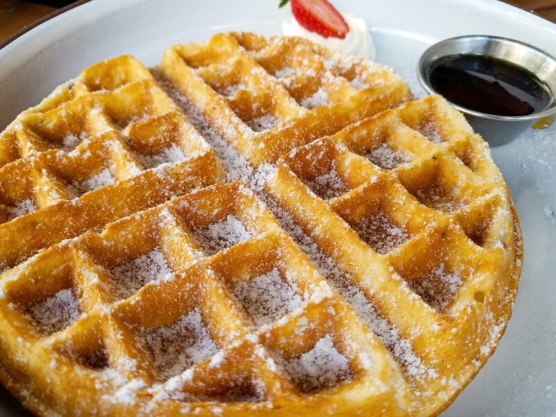 Close-up photo of a waffle covered in powdered sugar, as an example of holidays around the world