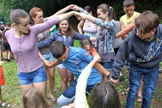 students holding hands tangled up together in a human knot