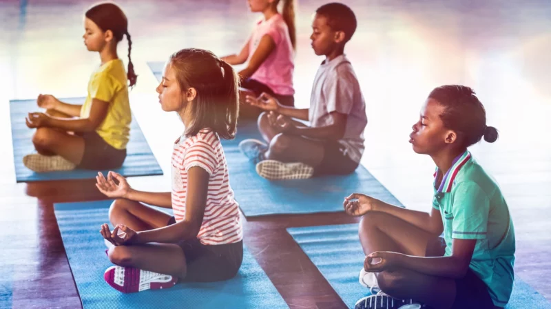 young students sitting on mats meditating, as an example of mindfulness activities for kids