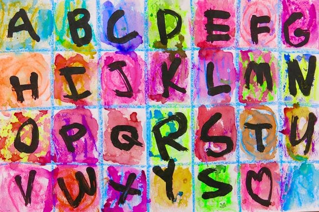 Paper divided into squares and painted different colors, with a letter of the alphabet in each square