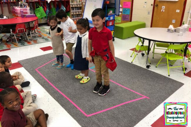 Children standing inside tape lines on the floor representing a boat (Kindergarten Math Games)
