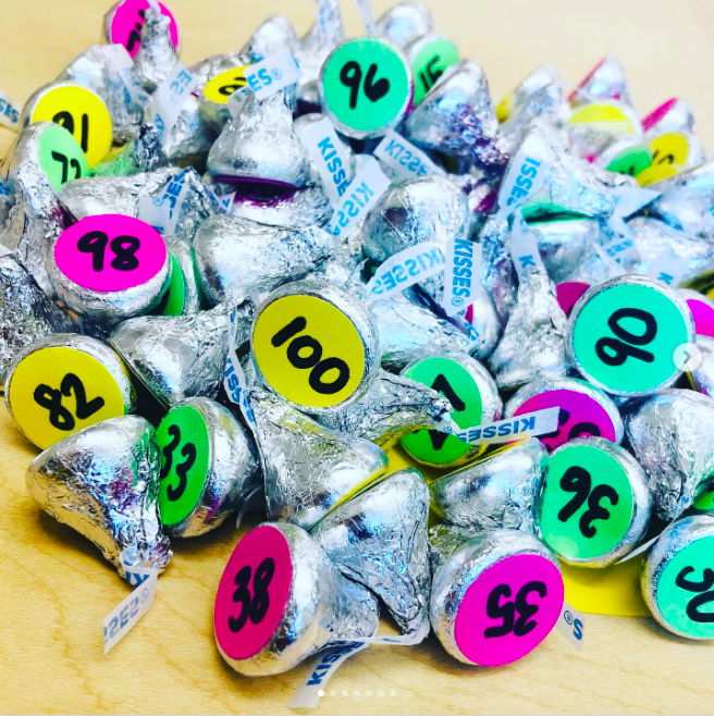 a pile of chocolate kisses with colored discs with numbers on them at the bottom