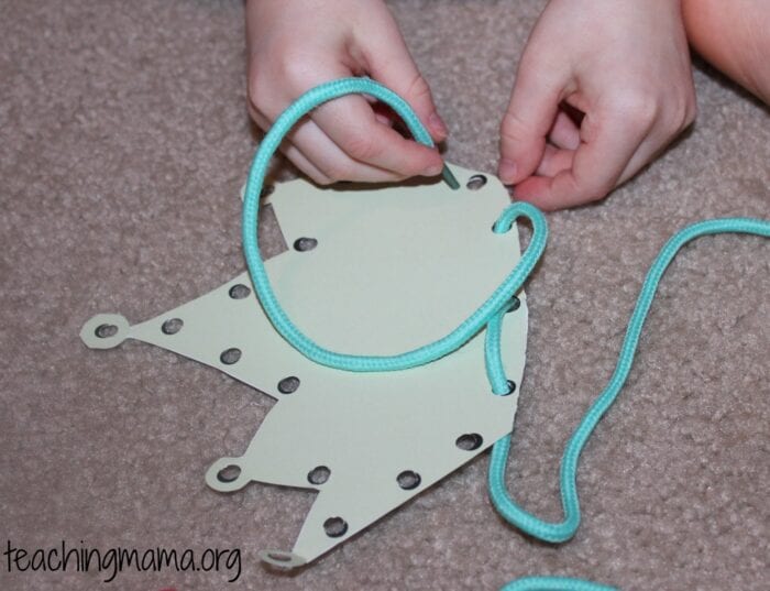 A preschooler laces a cord through holes in a lacing card