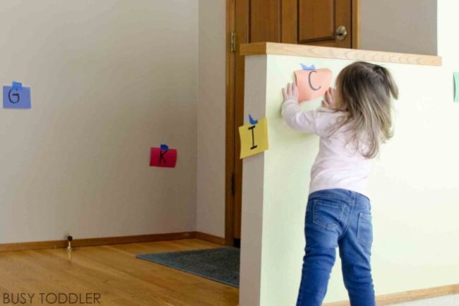 Child looking around a room to find letters taped to the wall