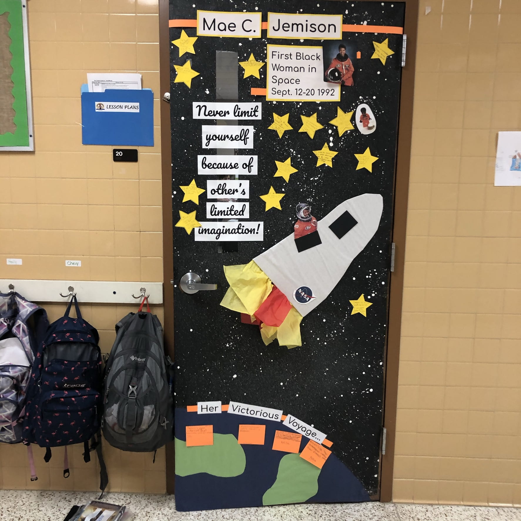 A classroom door has a rocketship on it shooting off from Earth. It says Mae C. Jemison. Text reads "never limit yourself because of others limited imagination." 