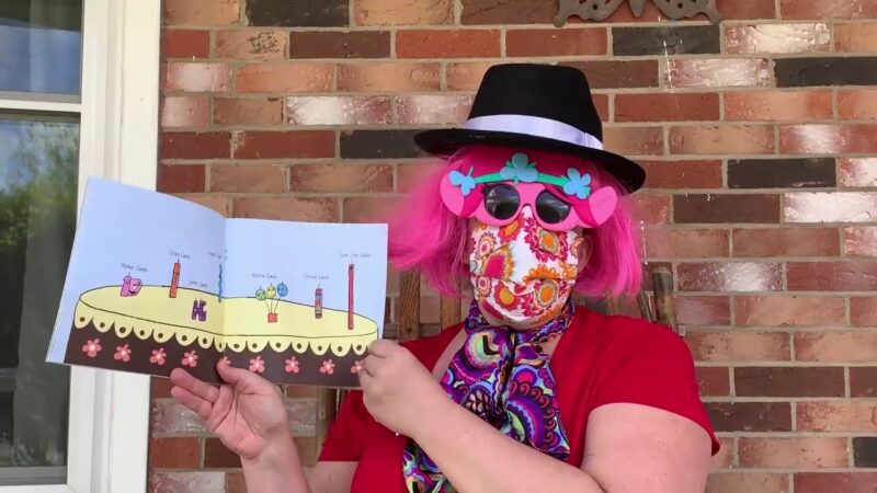 a person wearing a disguise reads a book to students 