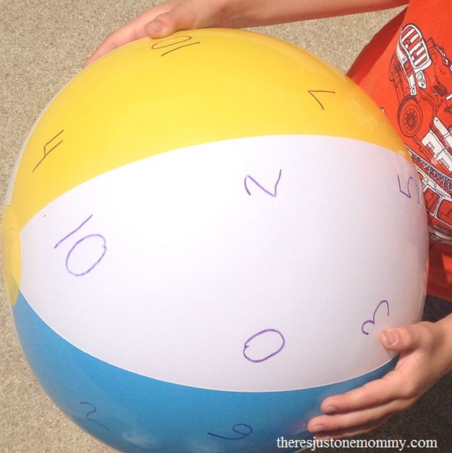 Student holding a beach ball with numbers written on it, used for math facts practice
