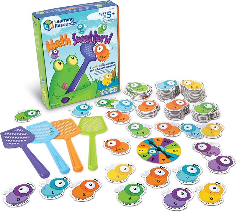 A board game box is shown with a cartoon frog on it sticking it's tongue out. There are several flies, several fly swatters, and a spinner with numbers also shown (math board games) 